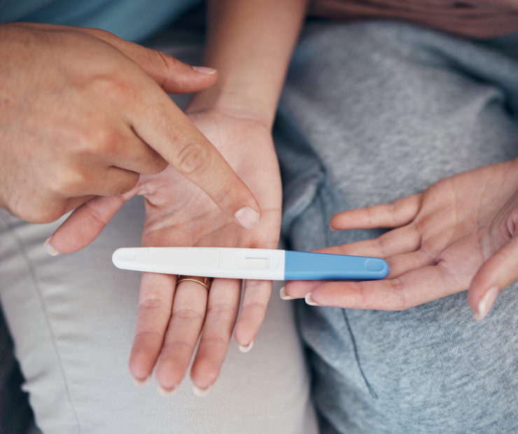 Hands, couple and closeup of pregnancy test, results and waiting for news together in home. Top view, kit and pregnant woman and man family planning for future maternity, ivf fertility and support