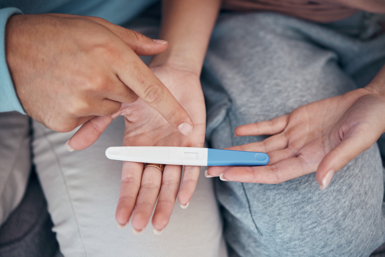 Hands, couple and closeup of pregnancy test, results and waiting for news together in home. Top view, kit and pregnant woman and man family planning for future maternity, ivf fertility and support